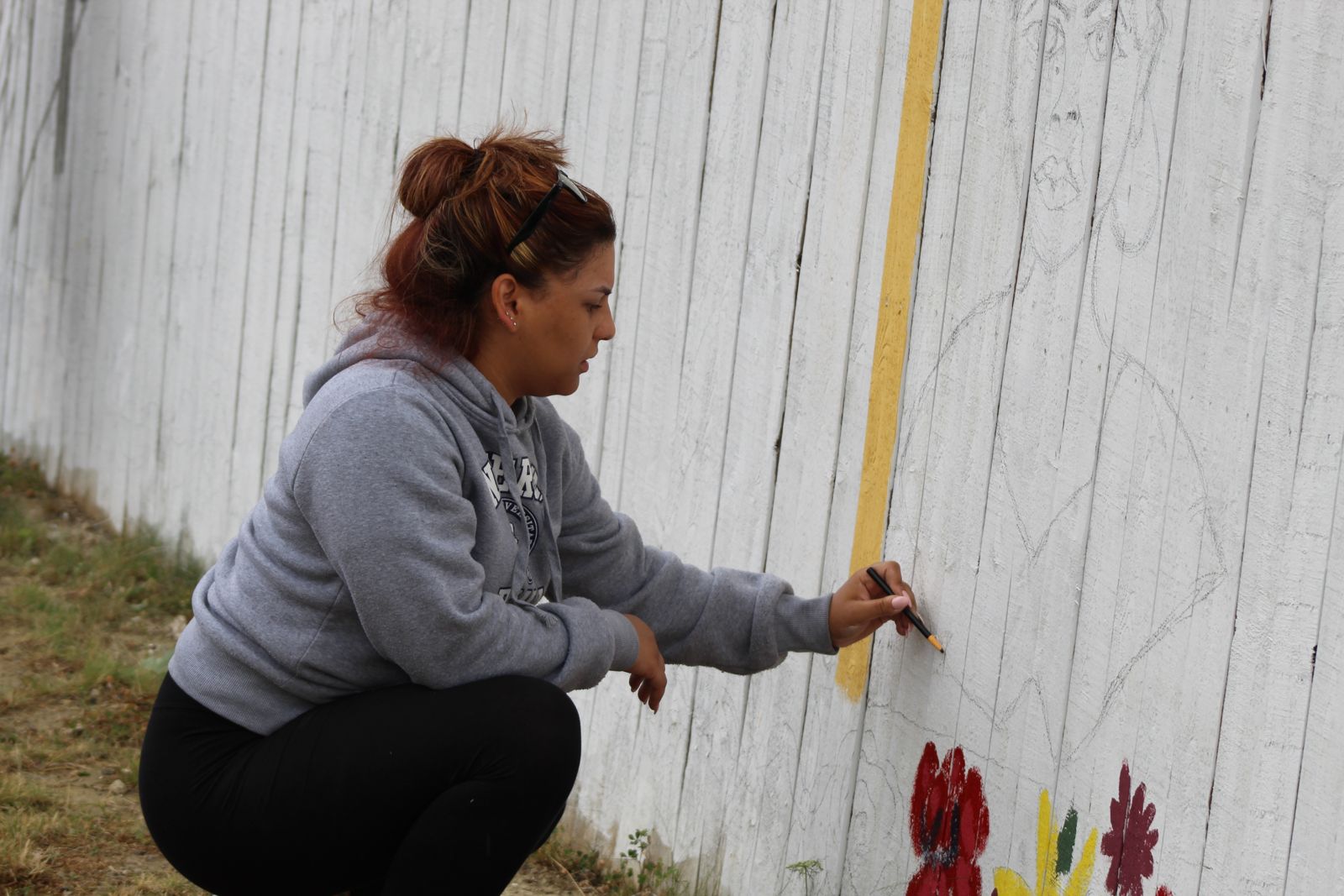 A volunteer painting roses on the Yorkshire Woods mural